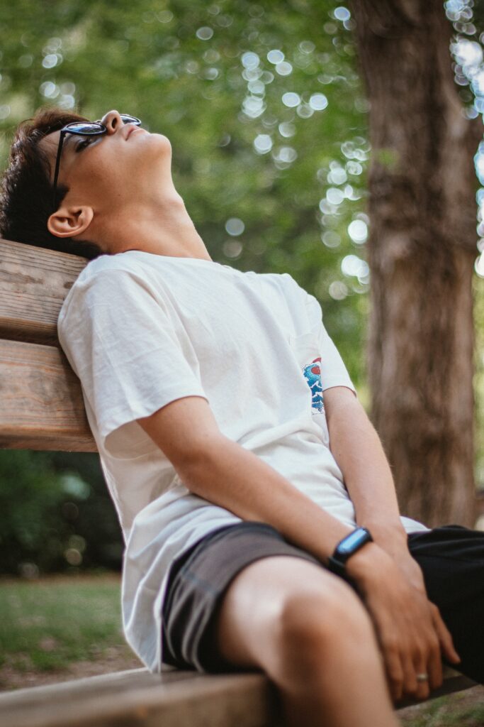 公園のベンチで空を見上げてひと休みする少年（就学以降）