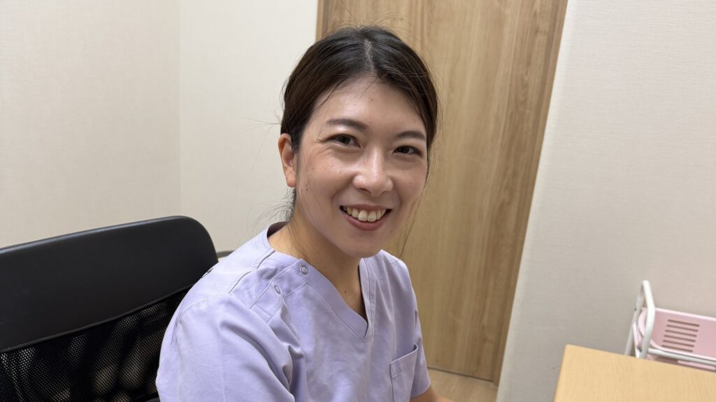 机の前で、こちらを向いて笑う栄養カウンセラーのちあき